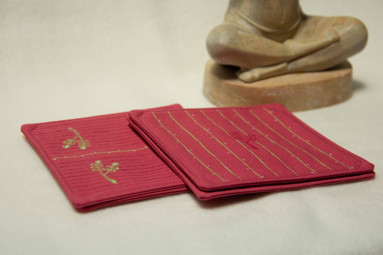 Four coasters with two different designs arranged next to a stone statue