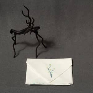 A folded handkerchief with a hand-painted floral design next to a small statue of a horse