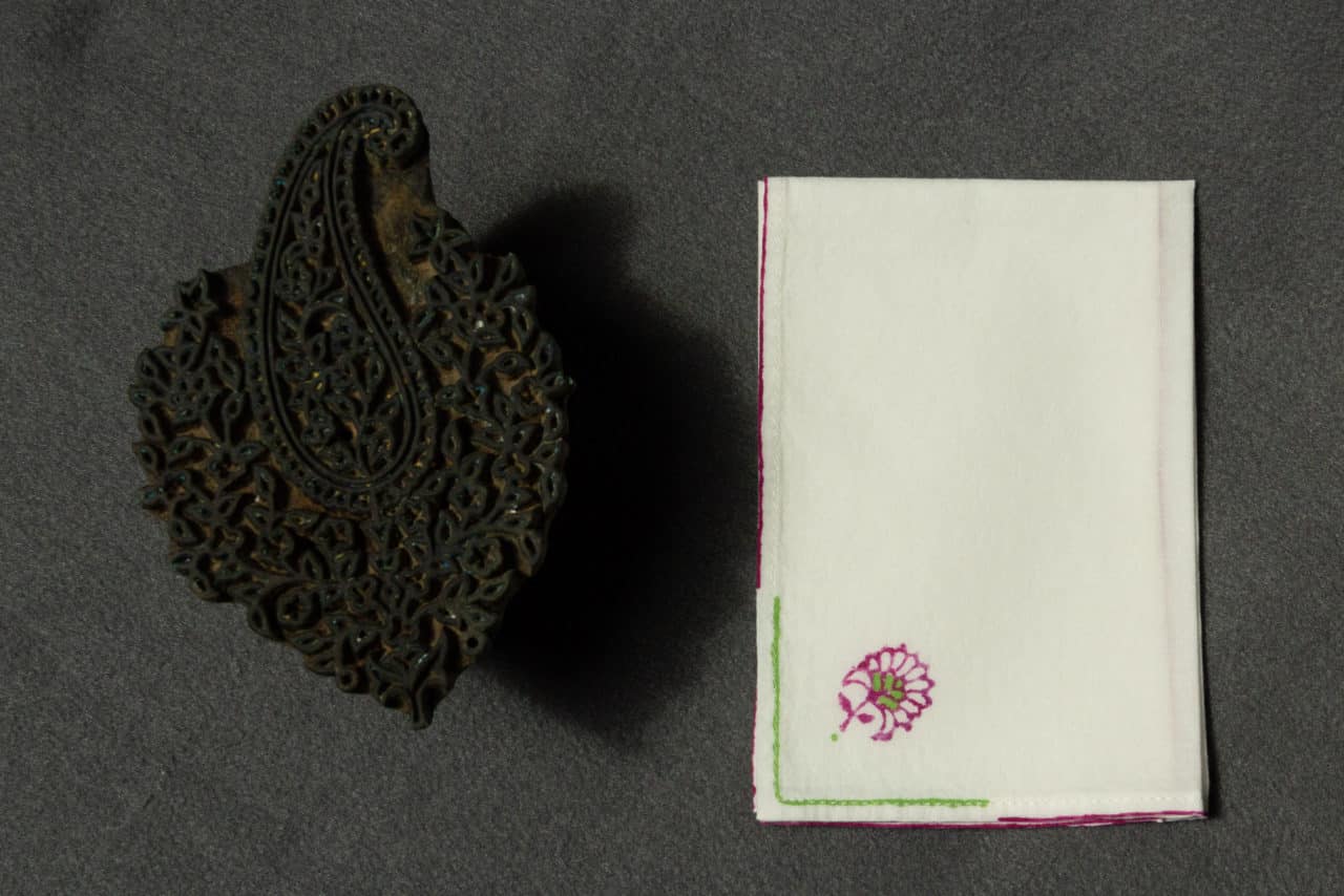 A folded handkerchief with a woodblock printed design next to a woodblock