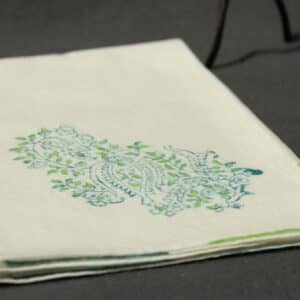 A folded handkerchief with a vintage woodblock print in green and blue