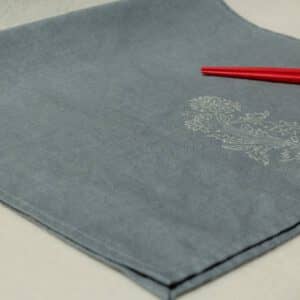 Blue-gray linen hand towel with floral print, and two red chopsticks