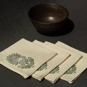 Four napkins with a woodblock print next to a ceramic bowl