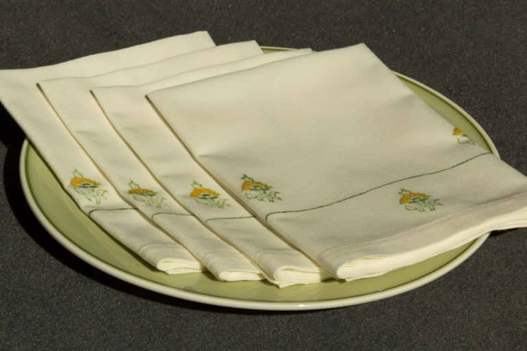 A set of four folded blockprinted napkins on a dinner plate