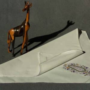 A partially folded handkerchief with a small wooden giraffe next to it