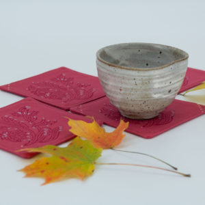 Four coasters with a ceramic cup and maple leaves