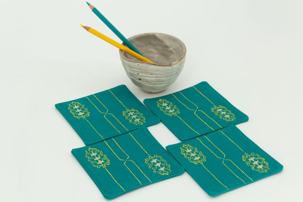 Four coasters with a ceramic cup and two color pencils