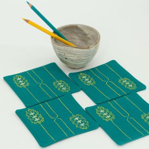 Four coasters with a ceramic cup and two color pencils