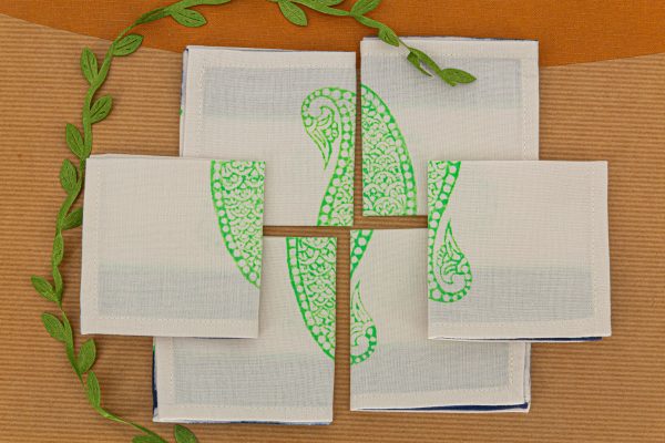 Six folded cocktail napkins on a book surface and a decorative ribbon