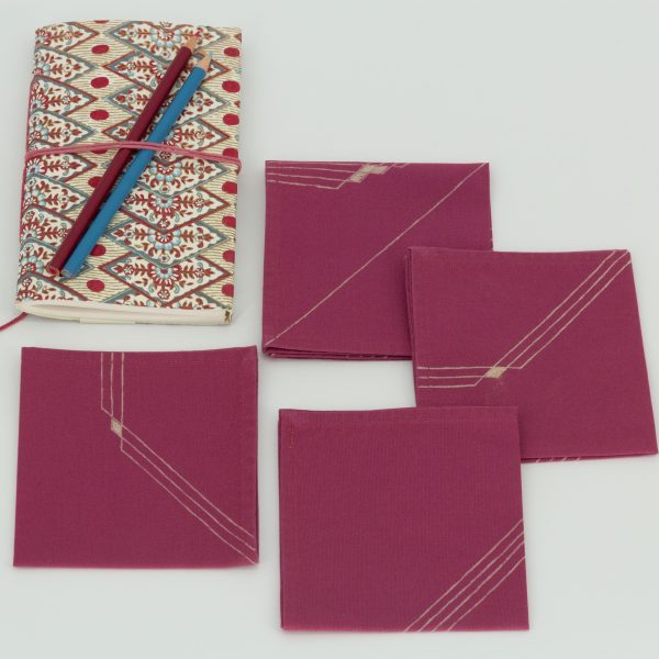 Four folded napkins with a book and two color pencils