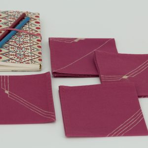 Four folded napkins with a book and two color pencils