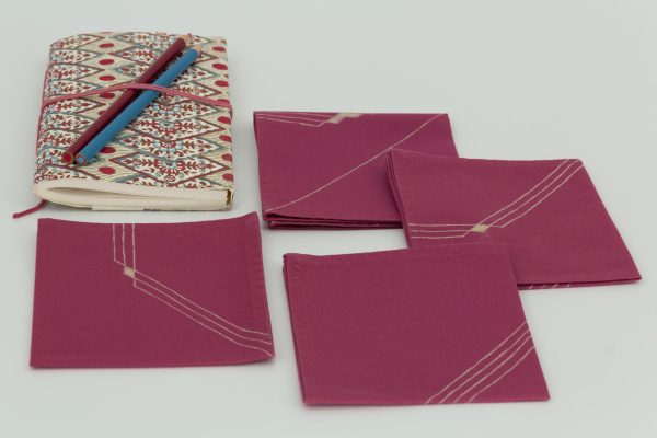 Four folded napkins with a book and two color pencils