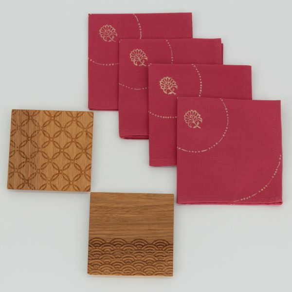 Four folded napkins next to two wooden coasters