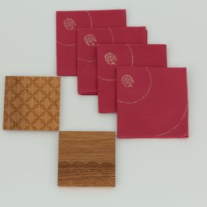 Four folded napkins next to two wooden coasters