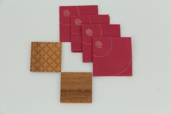 Four folded napkins next to two wooden coasters