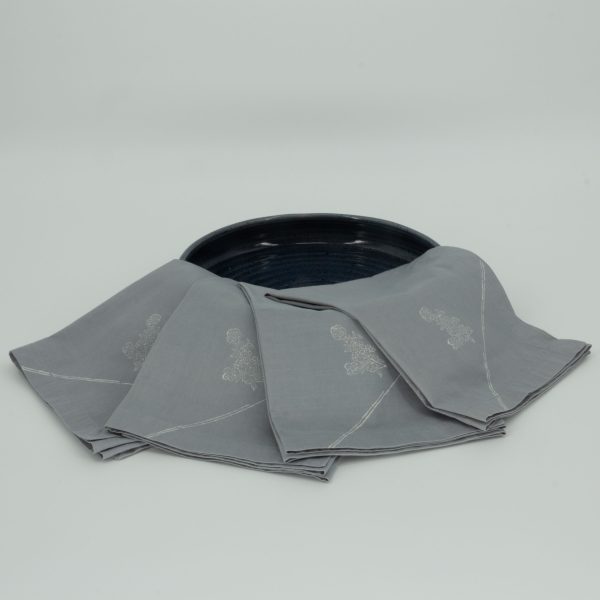 Four folded napkins draped over a wide ceramic dish