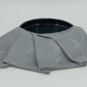 Four folded napkins draped over a wide ceramic dish