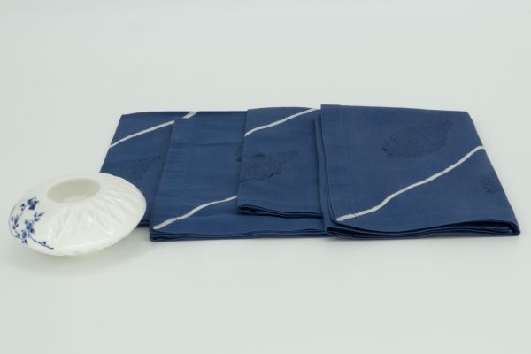 Four folded napkins with a small ceramic dish