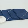 Four folded napkins with a small ceramic dish