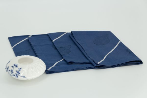 Four folded napkins with a small ceramic dish