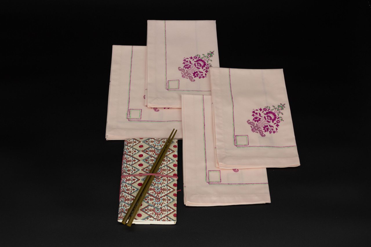 Four folded napkins with a notebook and two chopsticks