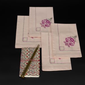 Four folded napkins with a notebook and two chopsticks