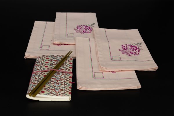 Four folded napkins with a notebook and two chopsticks