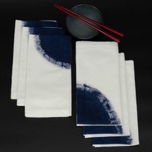 Six folded napkins next to a ceramic bowl and two chopsticks