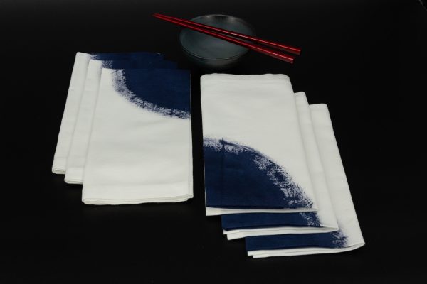 Six folded napkins next to a ceramic bowl and two chopsticks
