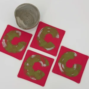 Four coasters next to a small ceramic cup