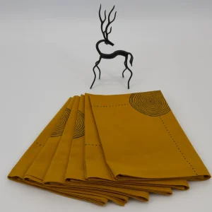 Six napkins folded and placed next to a small metal image of a deer