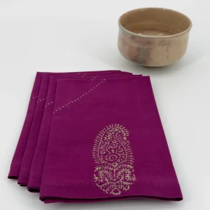 A set of four folded napkins next to a ceramic bowl