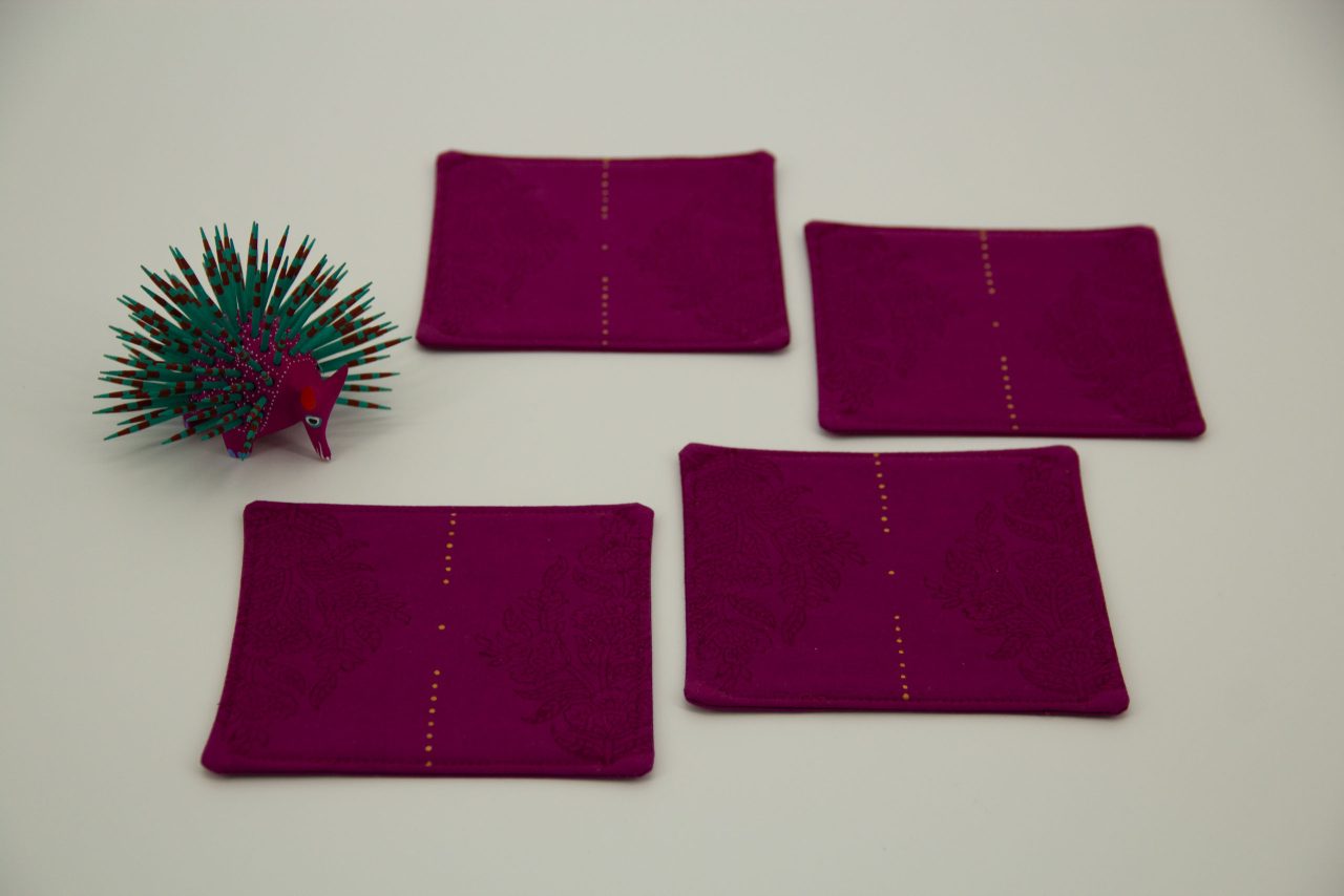 Four coasters next to a small figurine of a porcupine