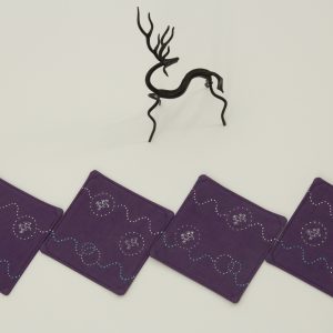 Four coasters next to a small metal sculpture of a deer