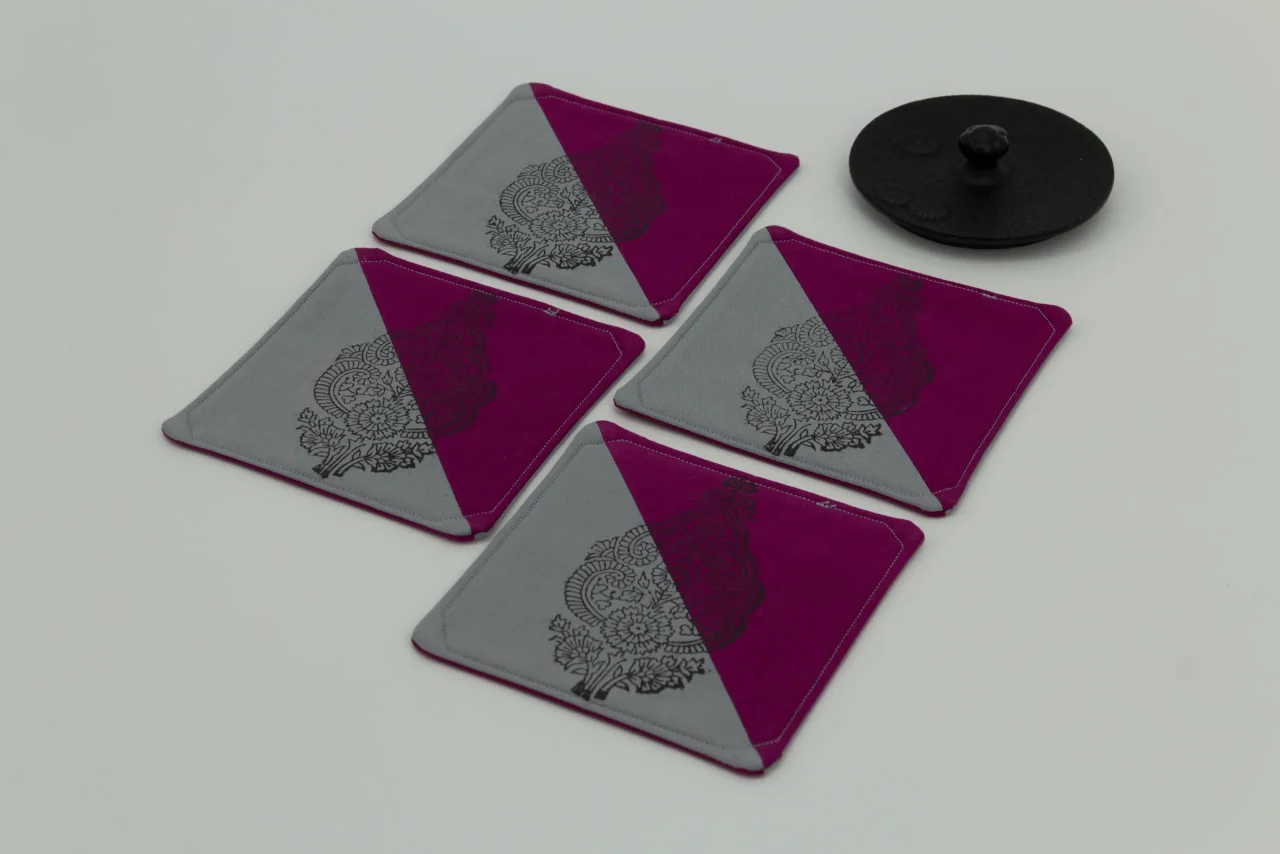 Four coasters next to the lid of an iron kettle